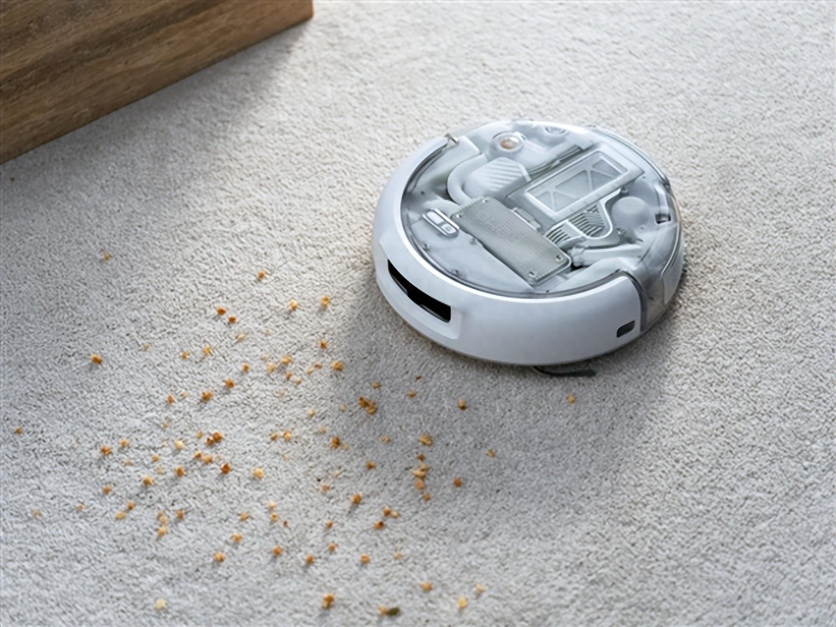Robot de balayage et de nettoyage DJI ROMO 2 &middot; Le robot est sur le tapis et il y a des particules de d&eacute;bris autour de lui qui doivent &ecirc;tre nettoy&eacute;s.jpeg